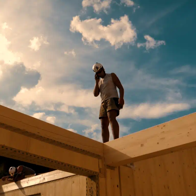 Mitarbeiter auf Balken eines Massivholzhauses