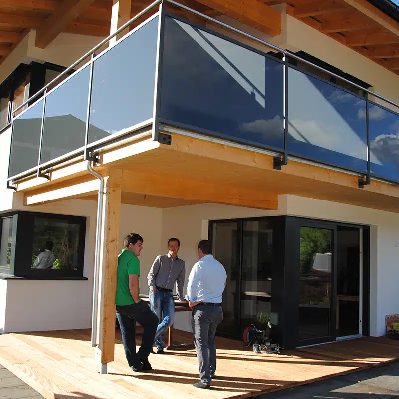 Personen die vor einem Vollholz Bau stehen und sich unterhalten