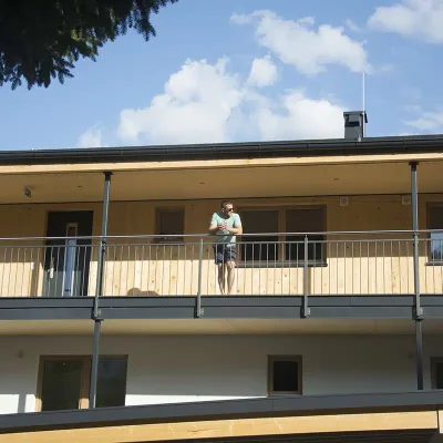 Außenanlage des Bauvorhabens Forstau mit einer Person am Balkon